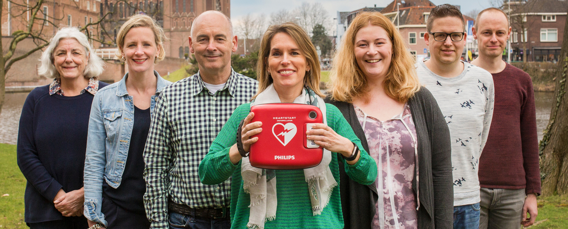 Buurtbewoners houden trots een AED defibrillator vast.
